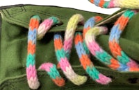 a pair of green converse sneakers with colorful yarn