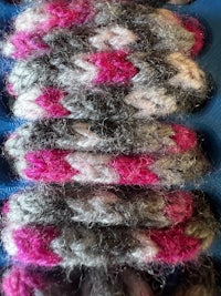 a row of pink and grey crocheted strands in a blue box