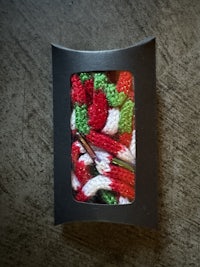 a black box with a red, green, and white knitted scarf