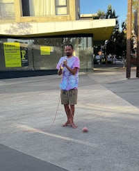 a man standing on a sidewalk with a rope