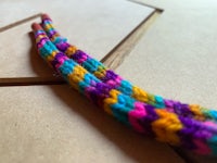 a colorful crocheted bracelet on top of a wooden table